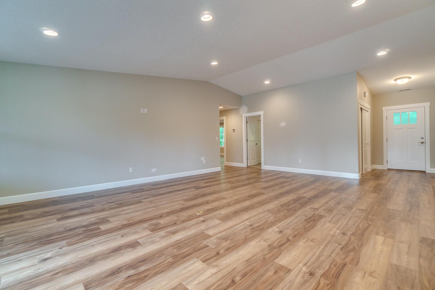 An empty living room with hardwood floors and white walls.