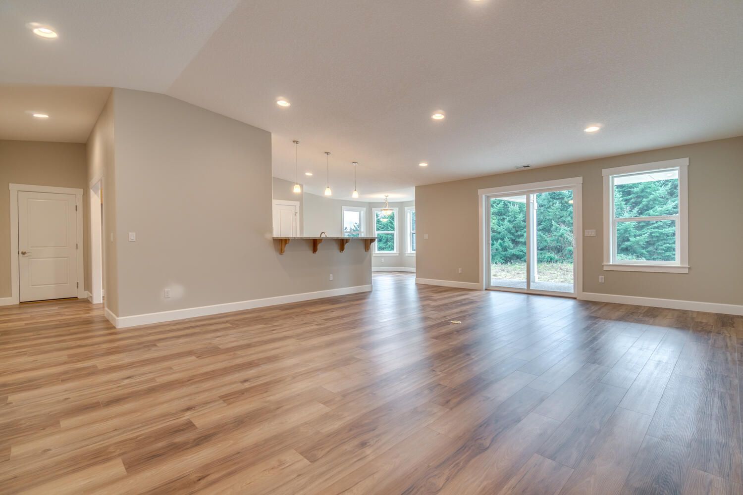An empty living room with hardwood floors and sliding glass doors.