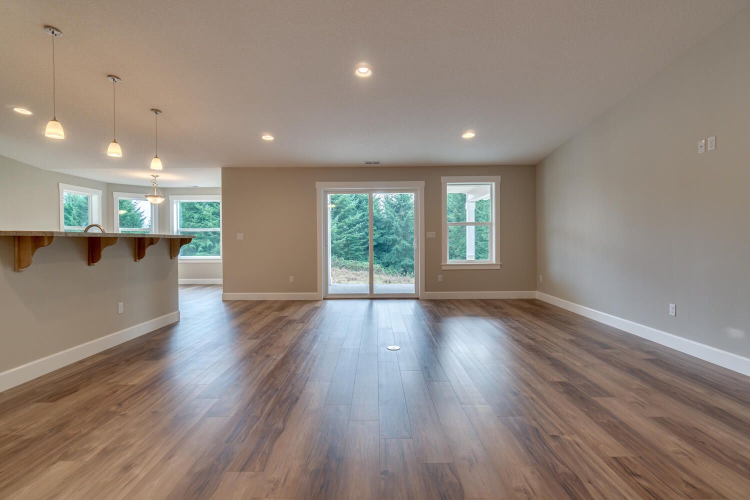 An empty living room with hardwood floors and sliding glass doors.