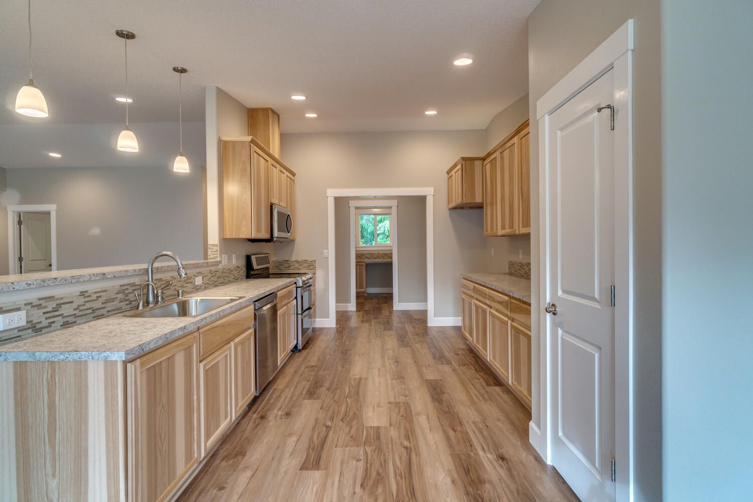 A kitchen with wooden cabinets , granite counter tops , stainless steel appliances , and hardwood floors.