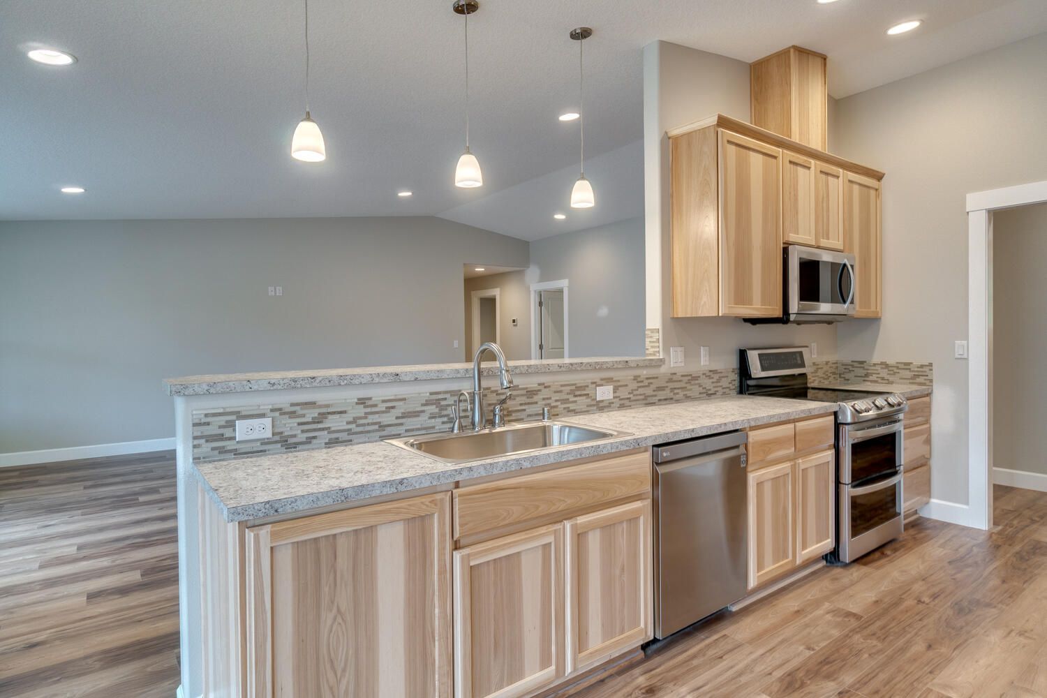 A kitchen with wooden cabinets , granite counter tops , stainless steel appliances and a sink.