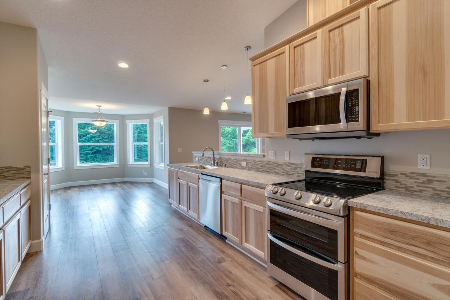 A kitchen with wooden cabinets , stainless steel appliances , a stove and a microwave.