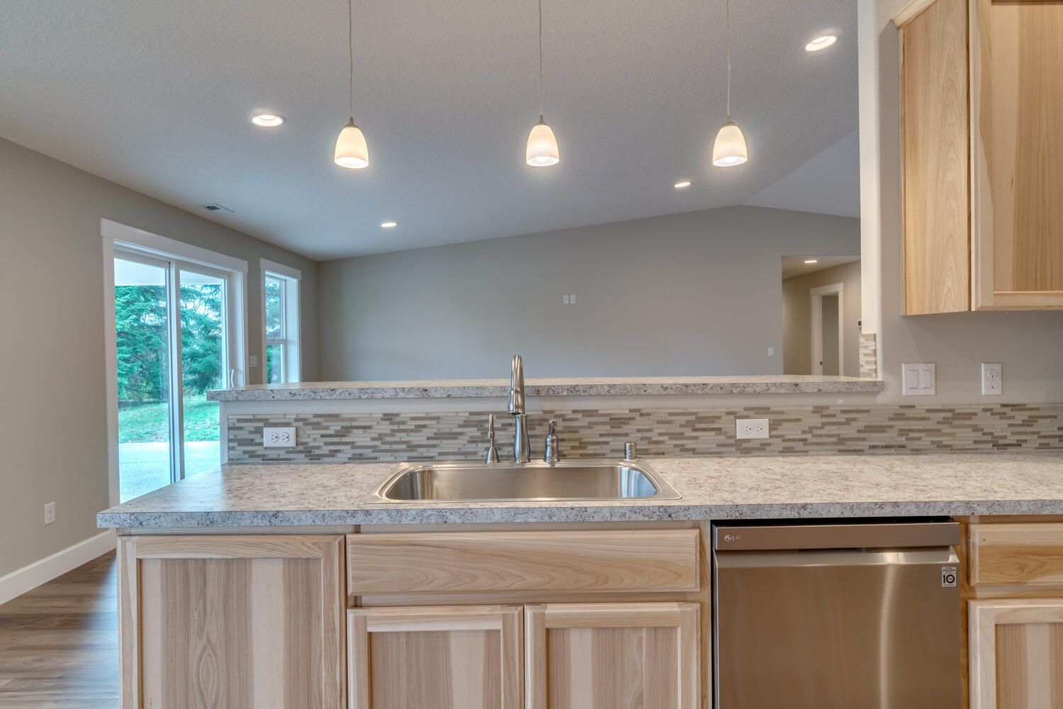 A kitchen with a sink , stainless steel dishwasher , and wooden cabinets.