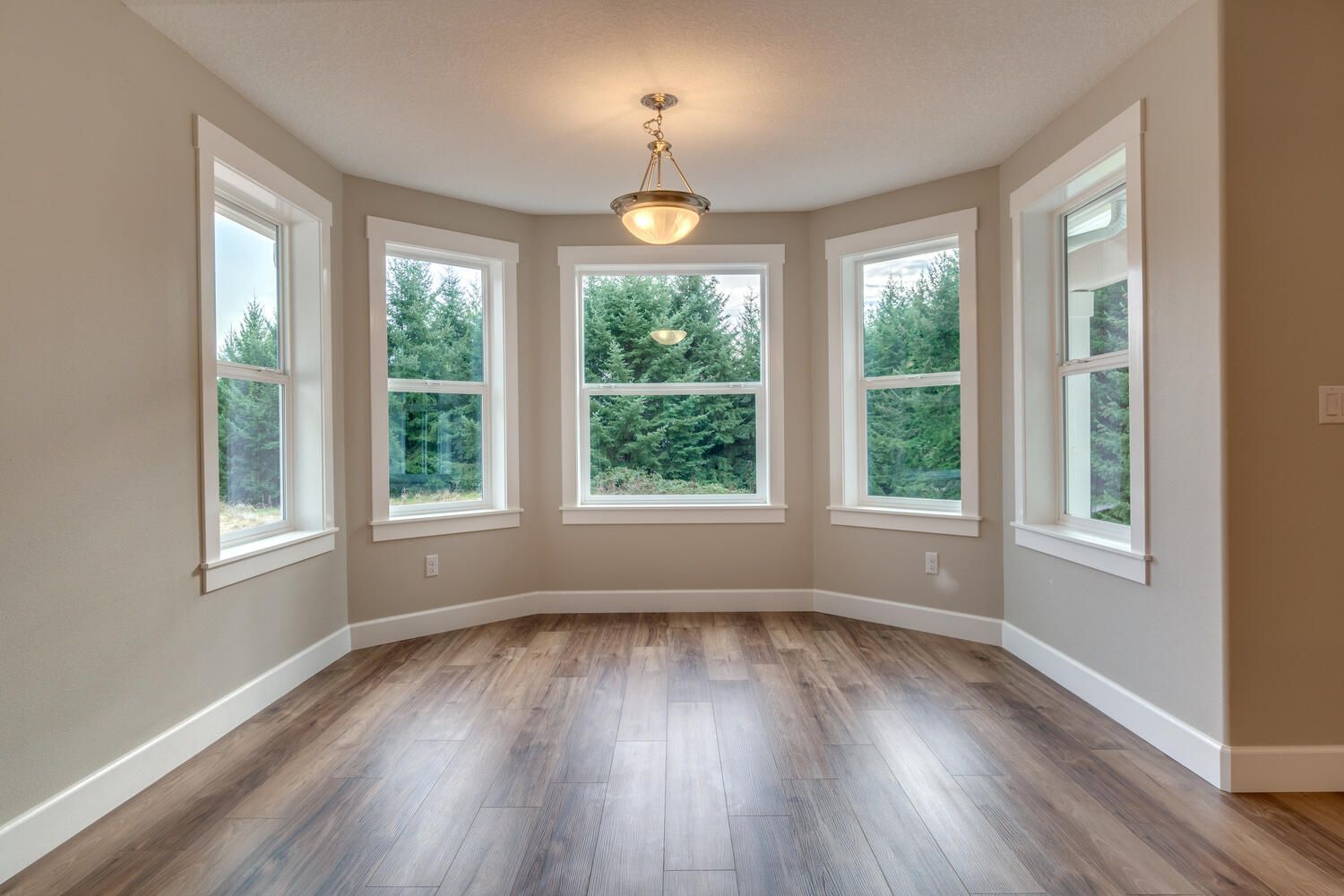 An empty room with hardwood floors and lots of windows.