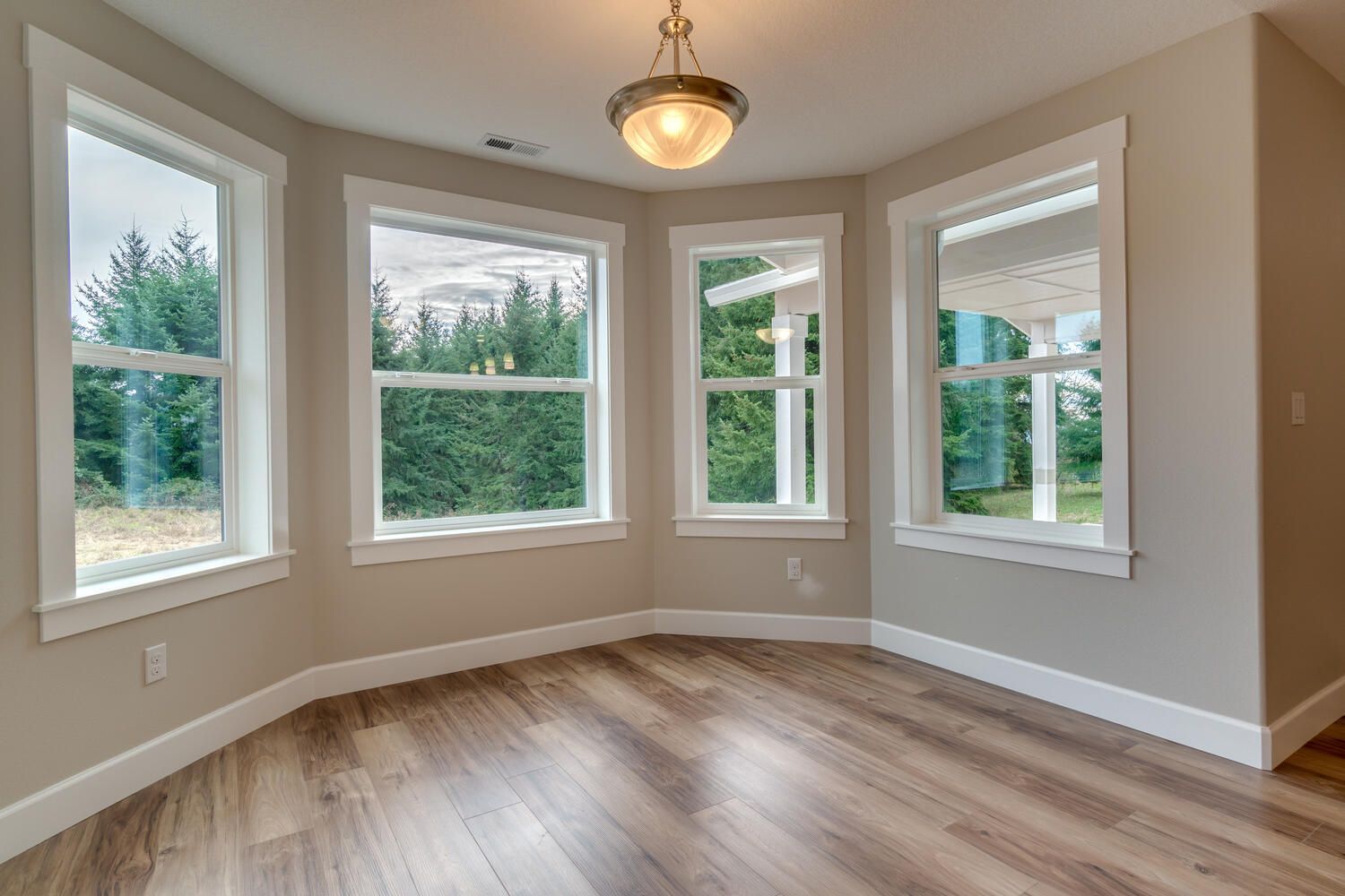 An empty room with hardwood floors and lots of windows.
