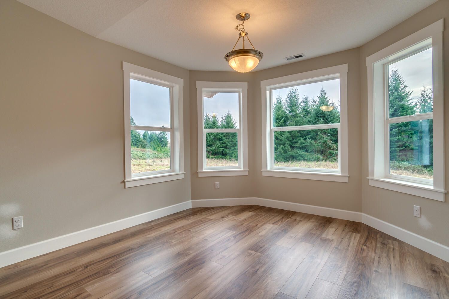 An empty room with hardwood floors and lots of windows.