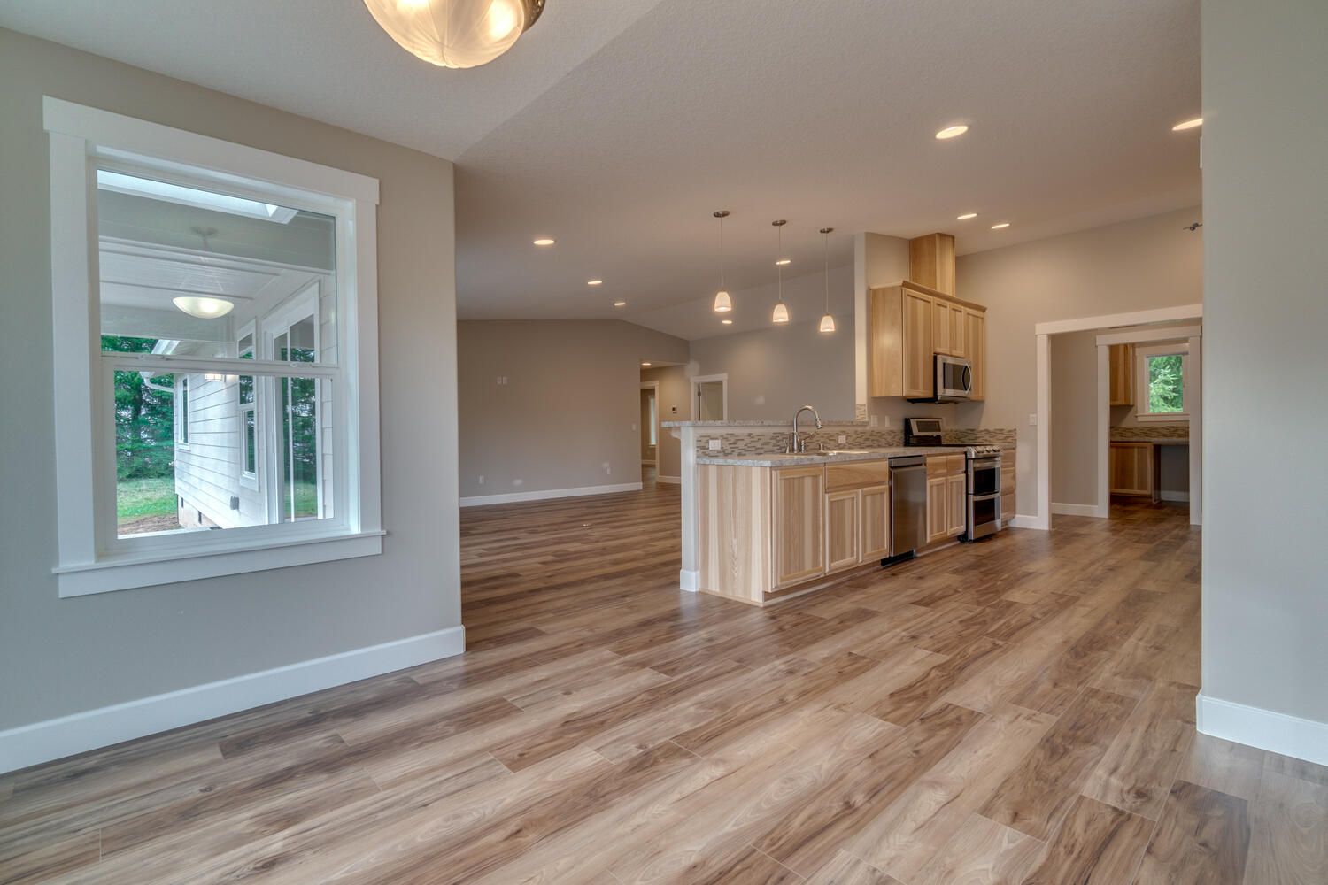 A large empty room with hardwood floors and a kitchen.