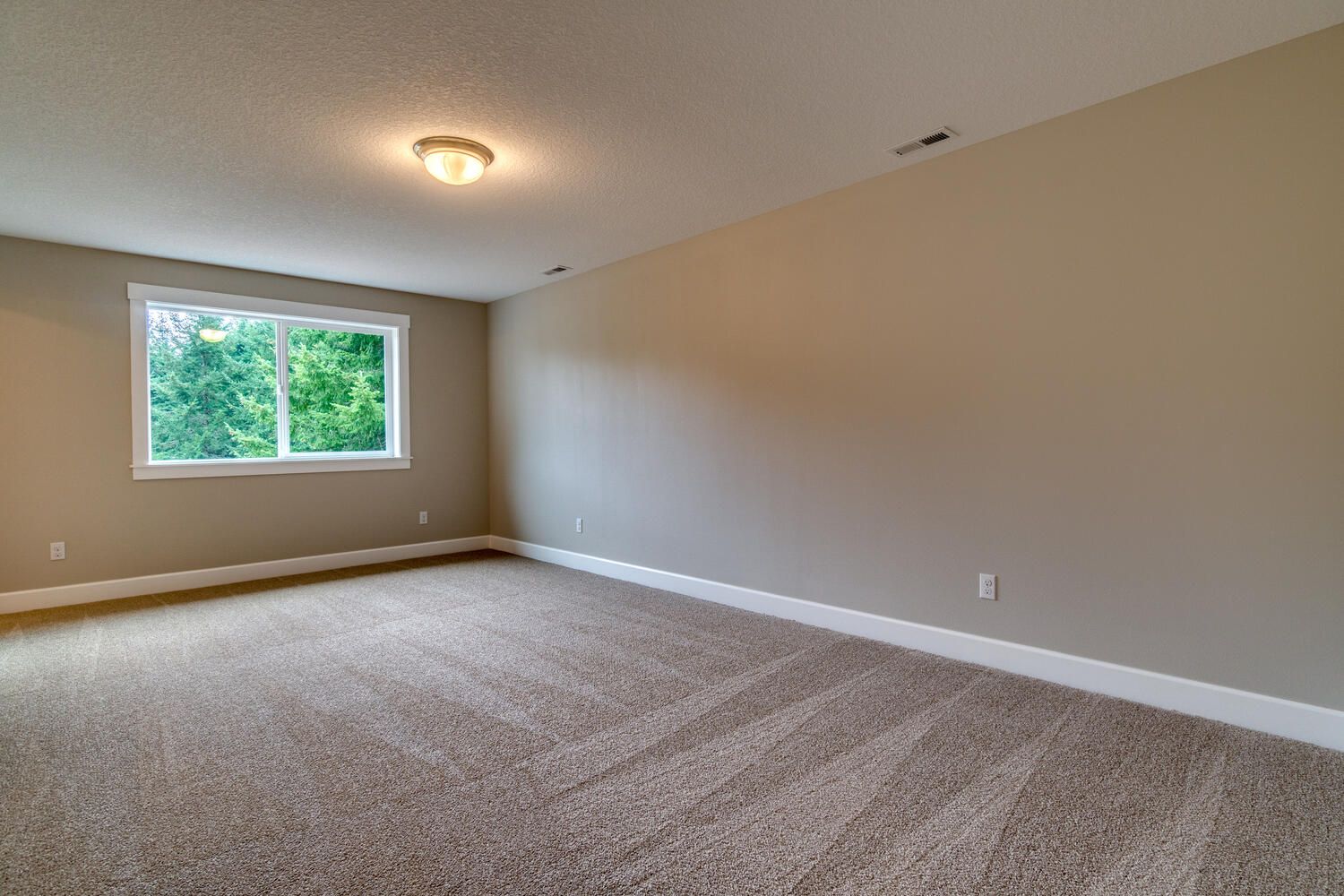 An empty room with a carpeted floor and a window.