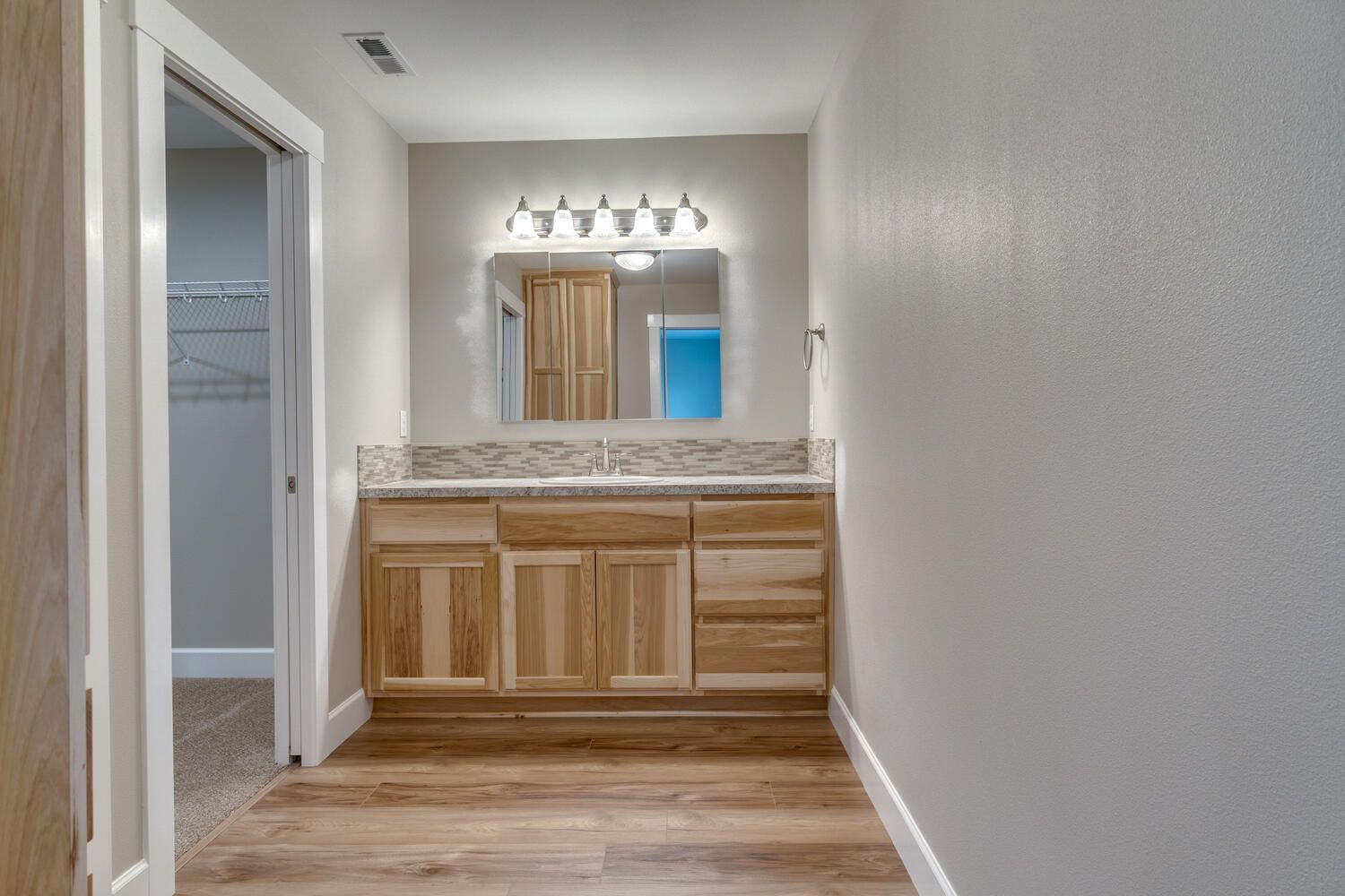 A bathroom with a sink , mirror and wooden cabinets.