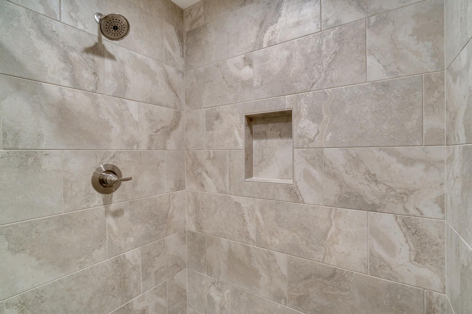 A shower with a shower head and a niche in the wall.