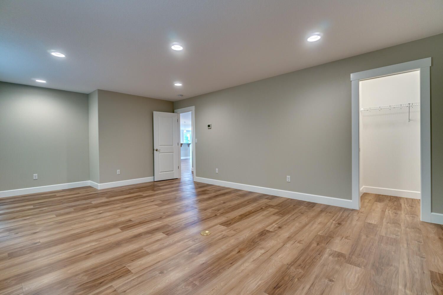 A large empty room with hardwood floors and gray walls.