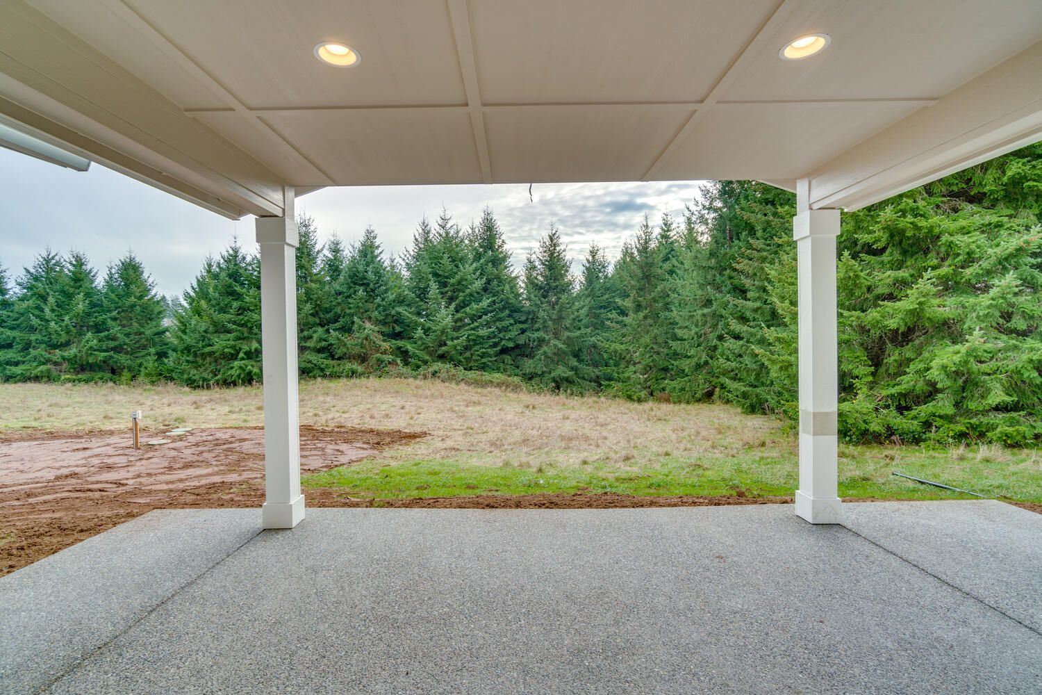 There is a covered patio with a view of a forest.