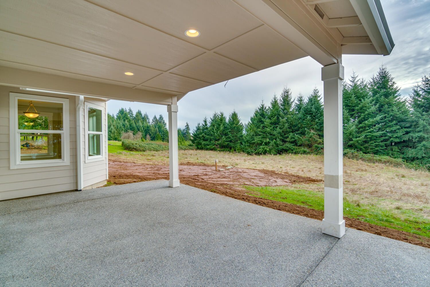 There is a covered patio with a view of a field and trees.
