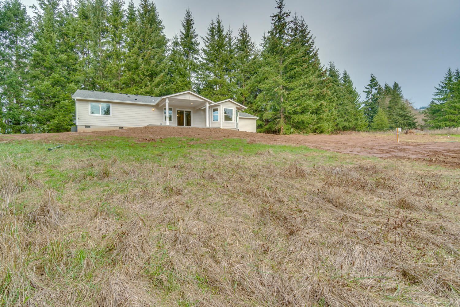 A house in the middle of a field with trees in the background