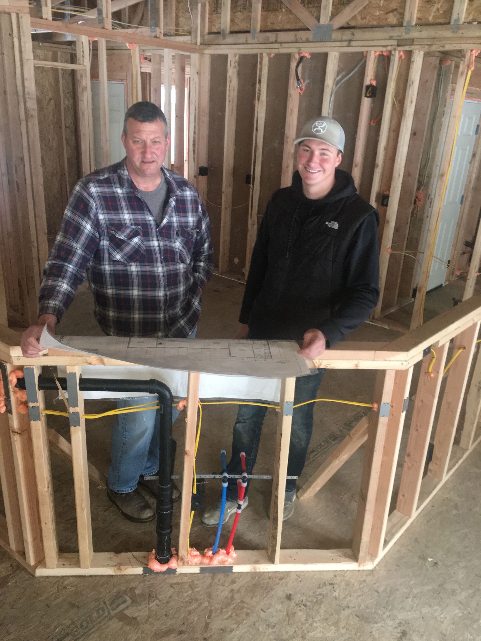 Two men standing next to each other in a building under construction