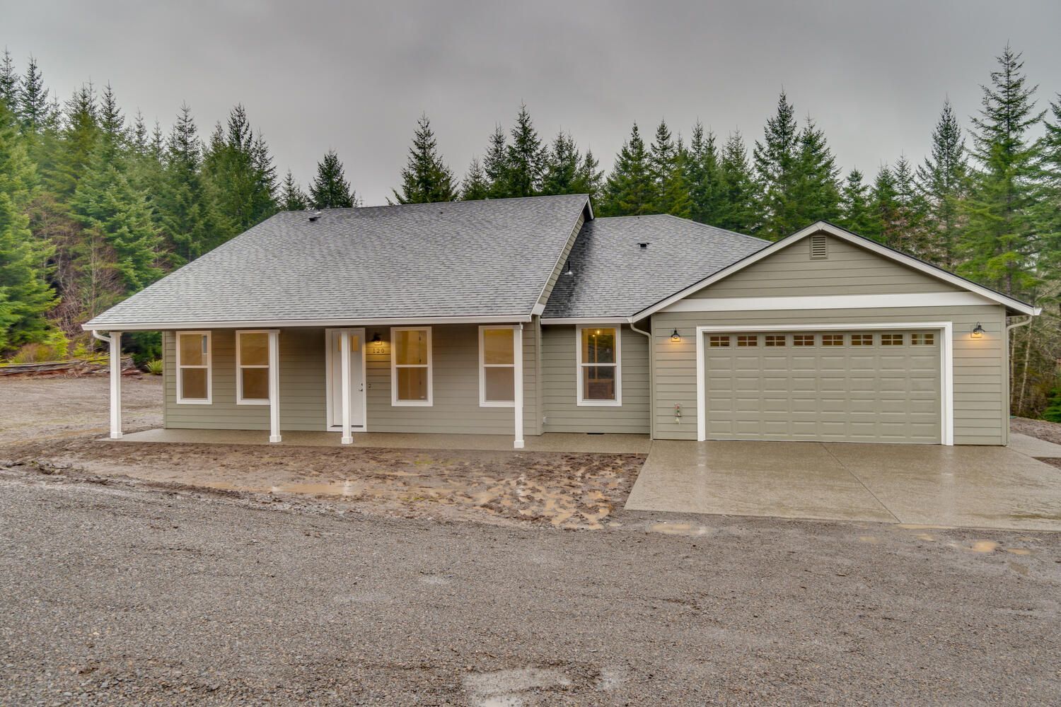 A house with a garage and a porch is surrounded by trees
