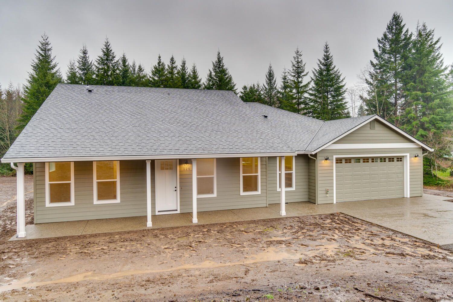 A house with a garage and a porch is surrounded by trees
