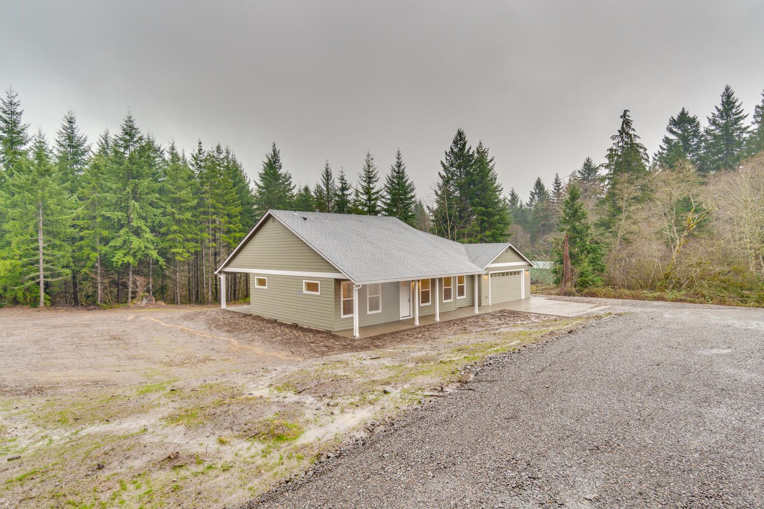 A house is sitting on the side of a dirt road in the middle of a forest.