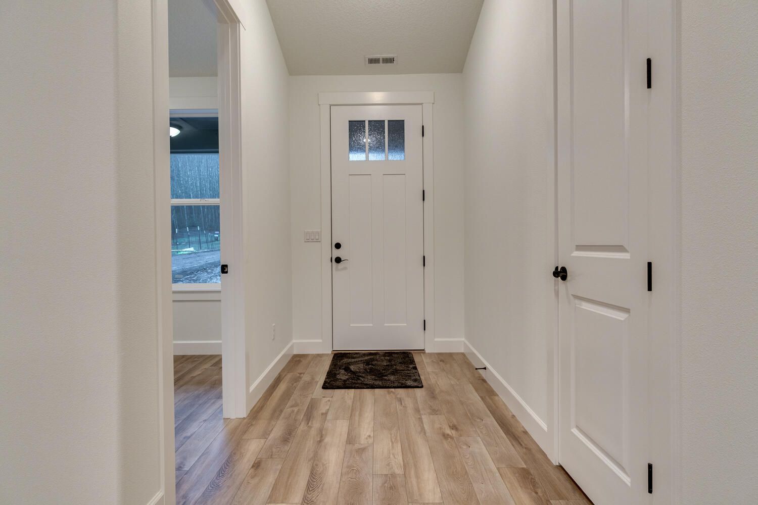 A hallway with hardwood floors and a white door in a house.