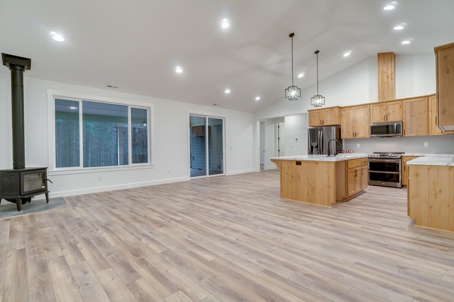 There is a wood stove in the middle of the room in the kitchen.