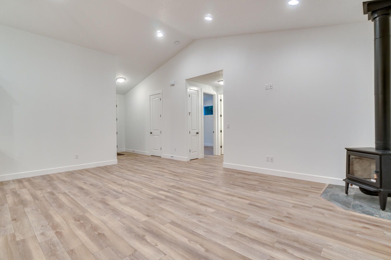An empty living room with hardwood floors and a wood stove.