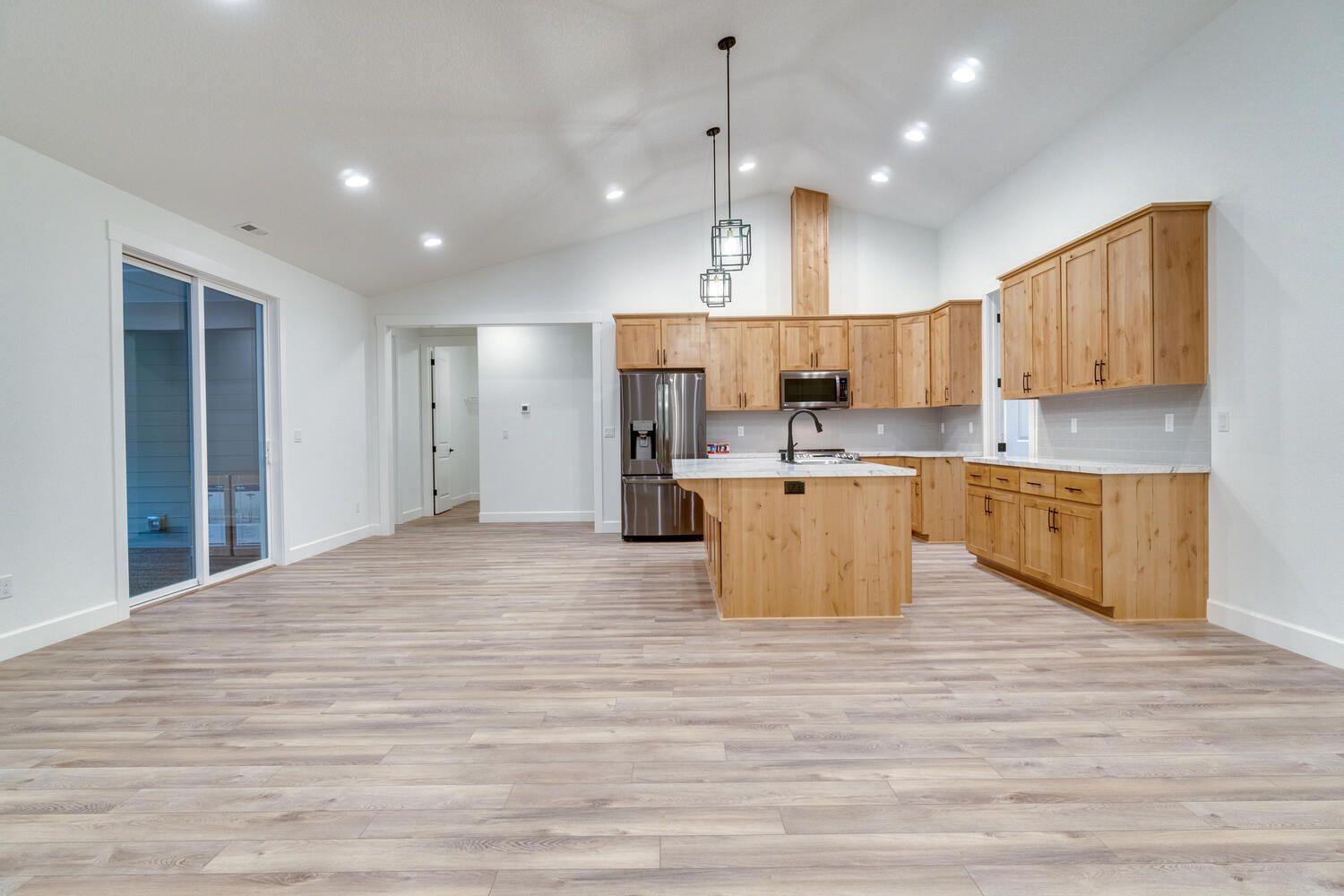 An empty kitchen with wooden cabinets and stainless steel appliances.