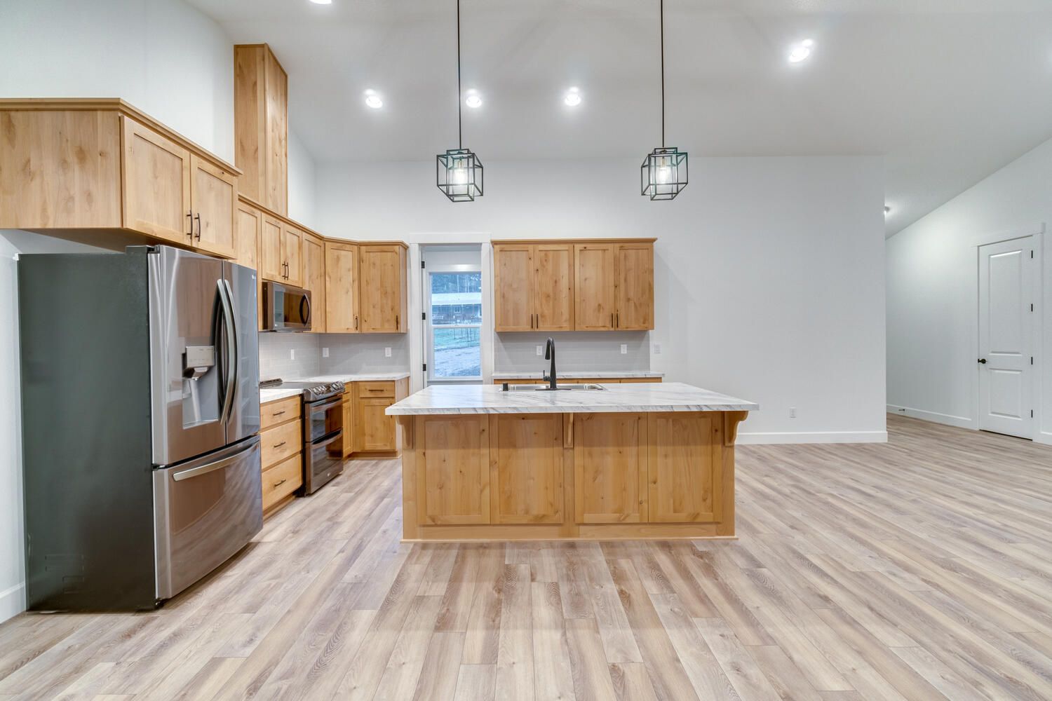 A kitchen with wooden cabinets , stainless steel appliances , and a large island.