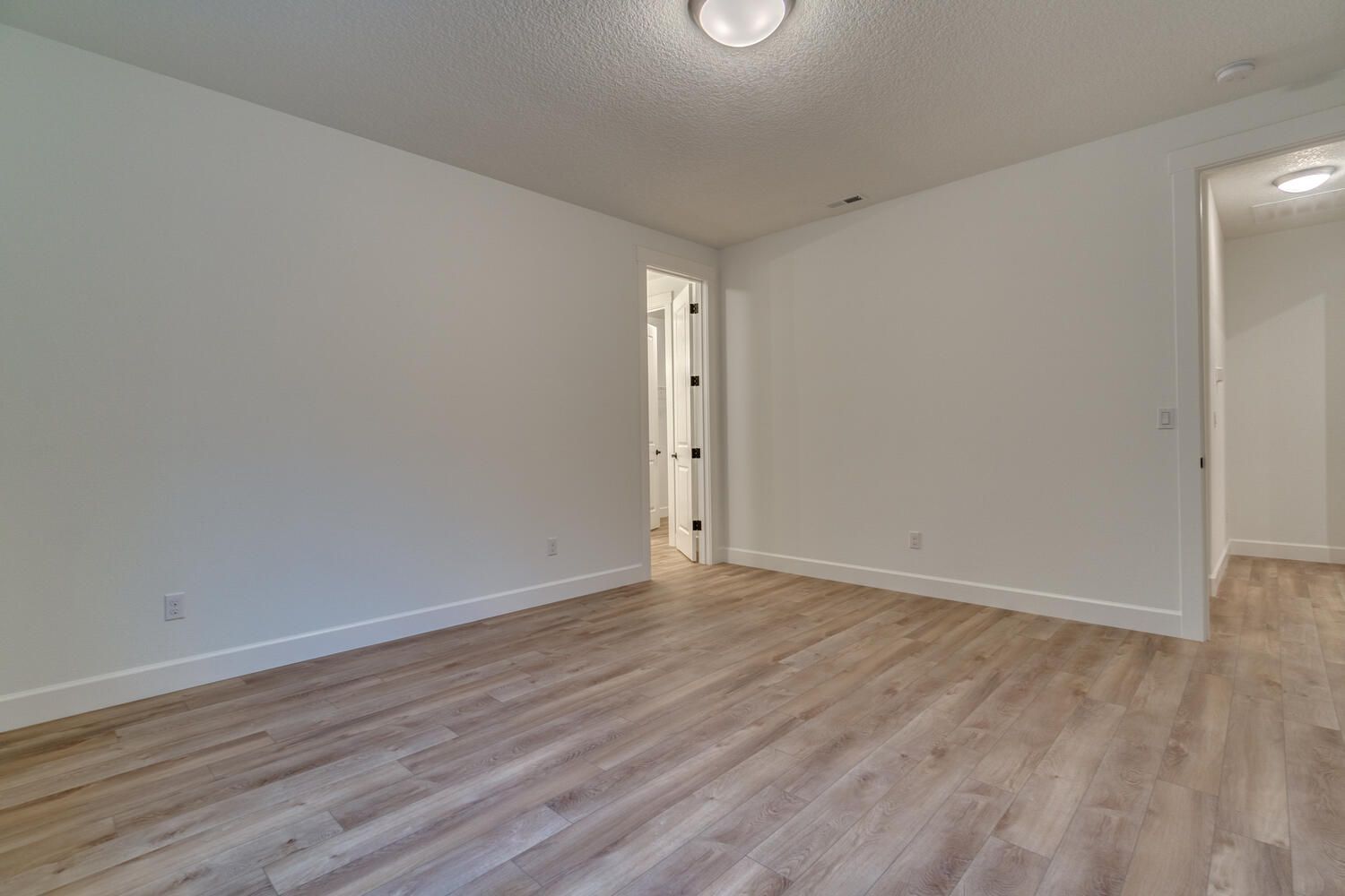 A large empty room with hardwood floors and white walls.