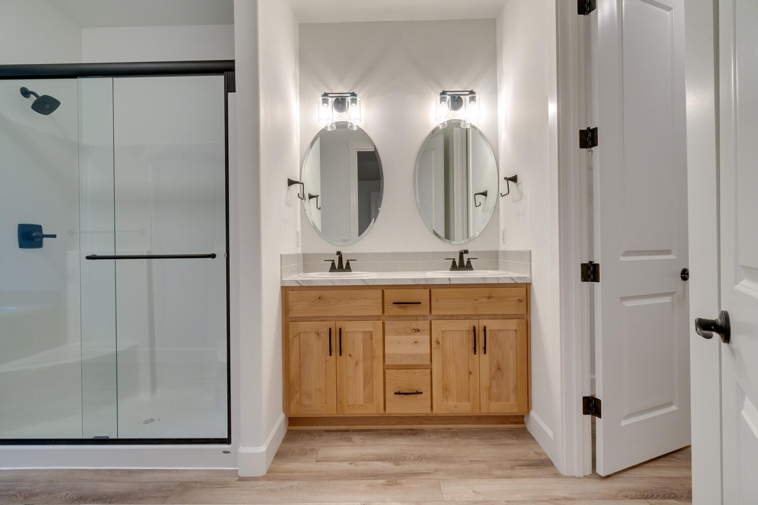 A bathroom with two sinks and a walk in shower.