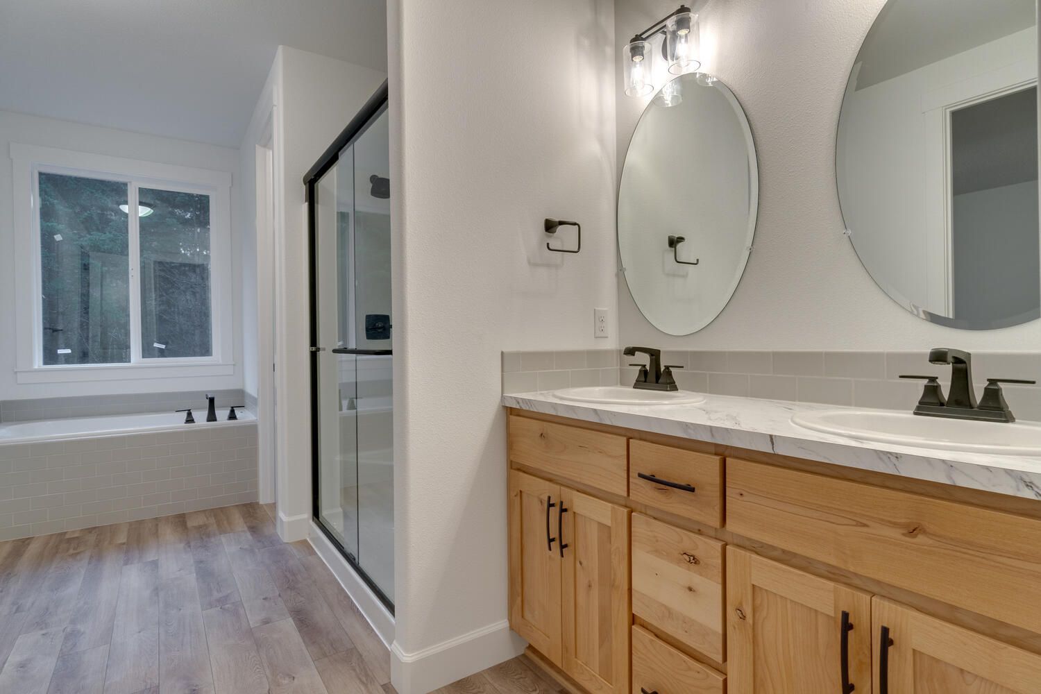 A bathroom with two sinks , two mirrors and a tub.
