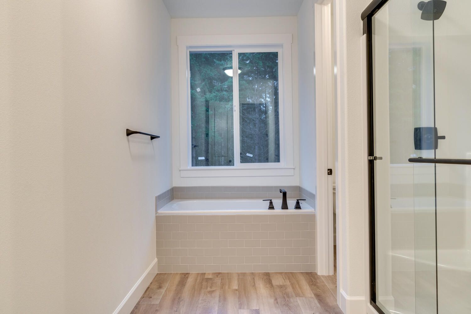A bathroom with a tub , shower and window.