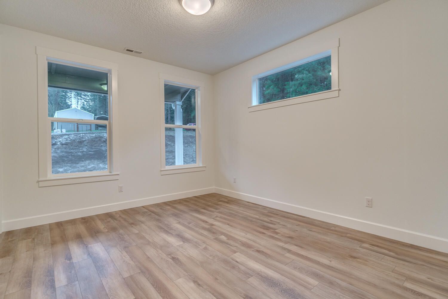 An empty room with hardwood floors and two windows.