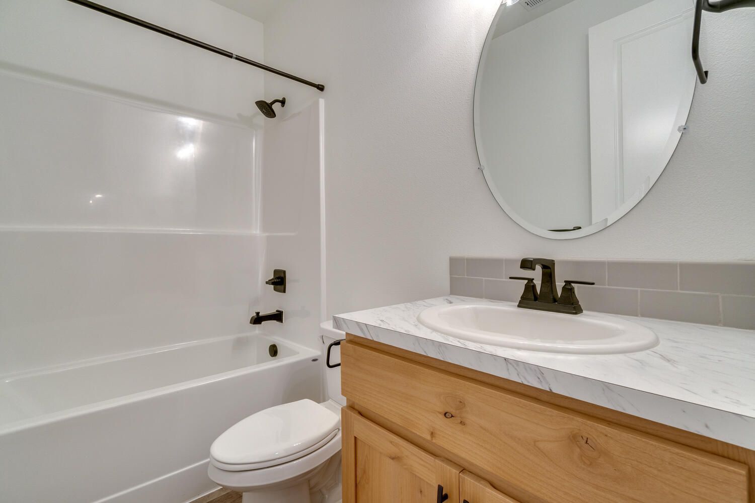 A bathroom with a toilet , sink , bathtub and mirror.