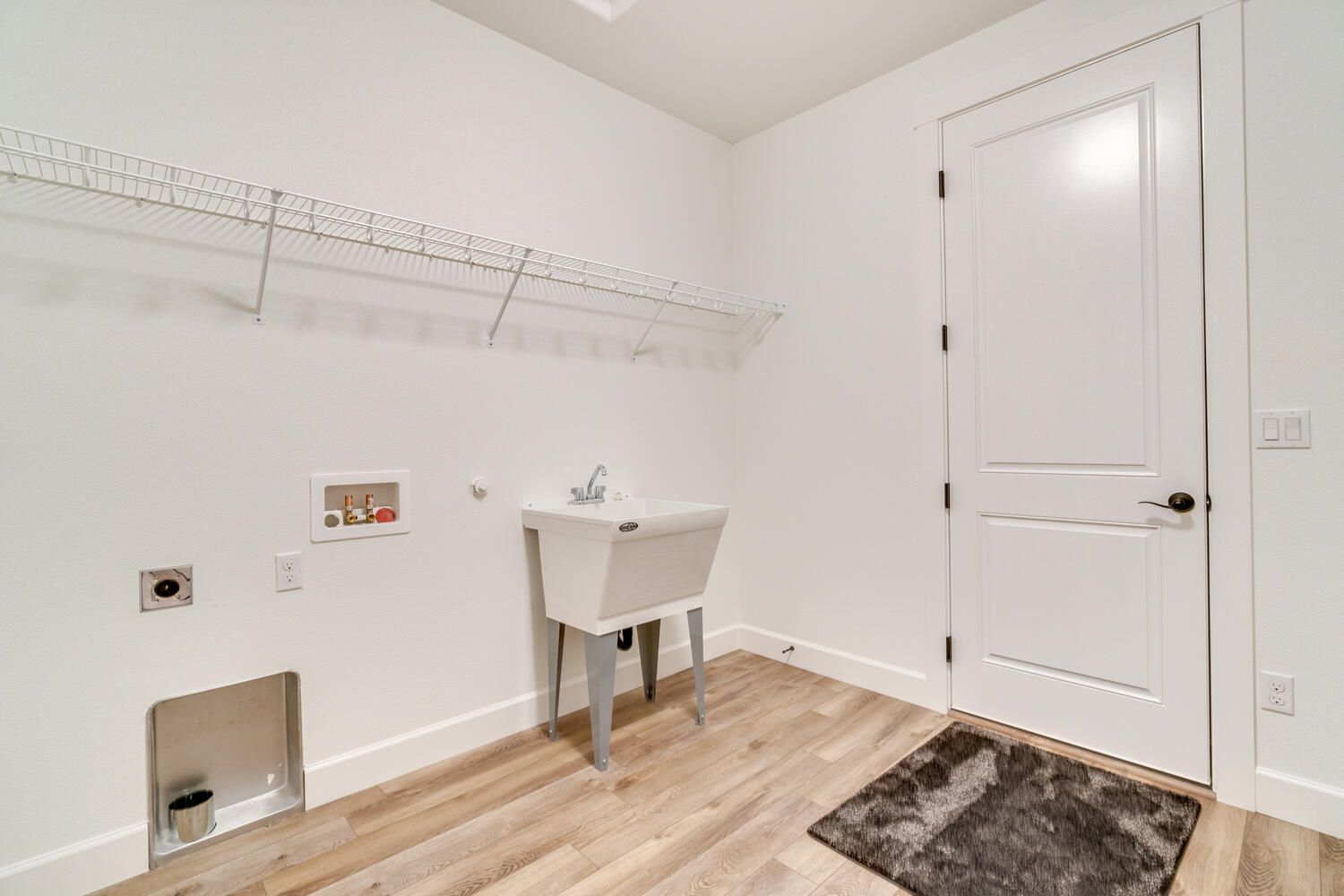 A laundry room with a sink and a door.