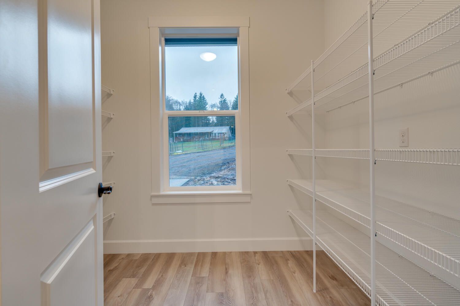 An empty walk in closet with shelves and a window.