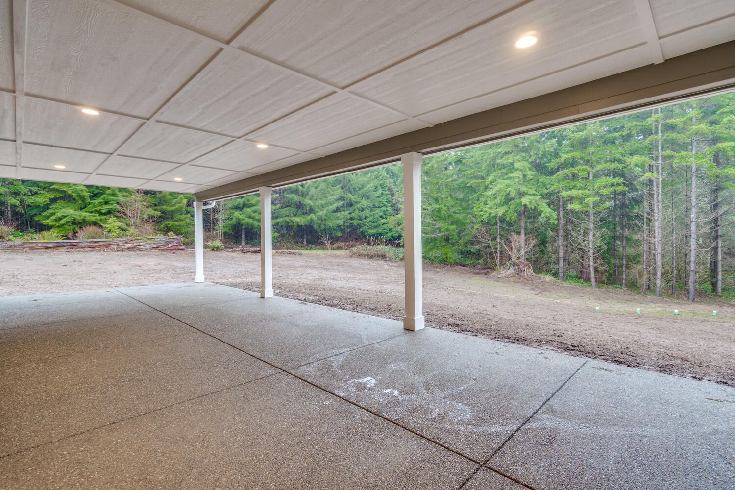 A covered patio with a view of a forest.
