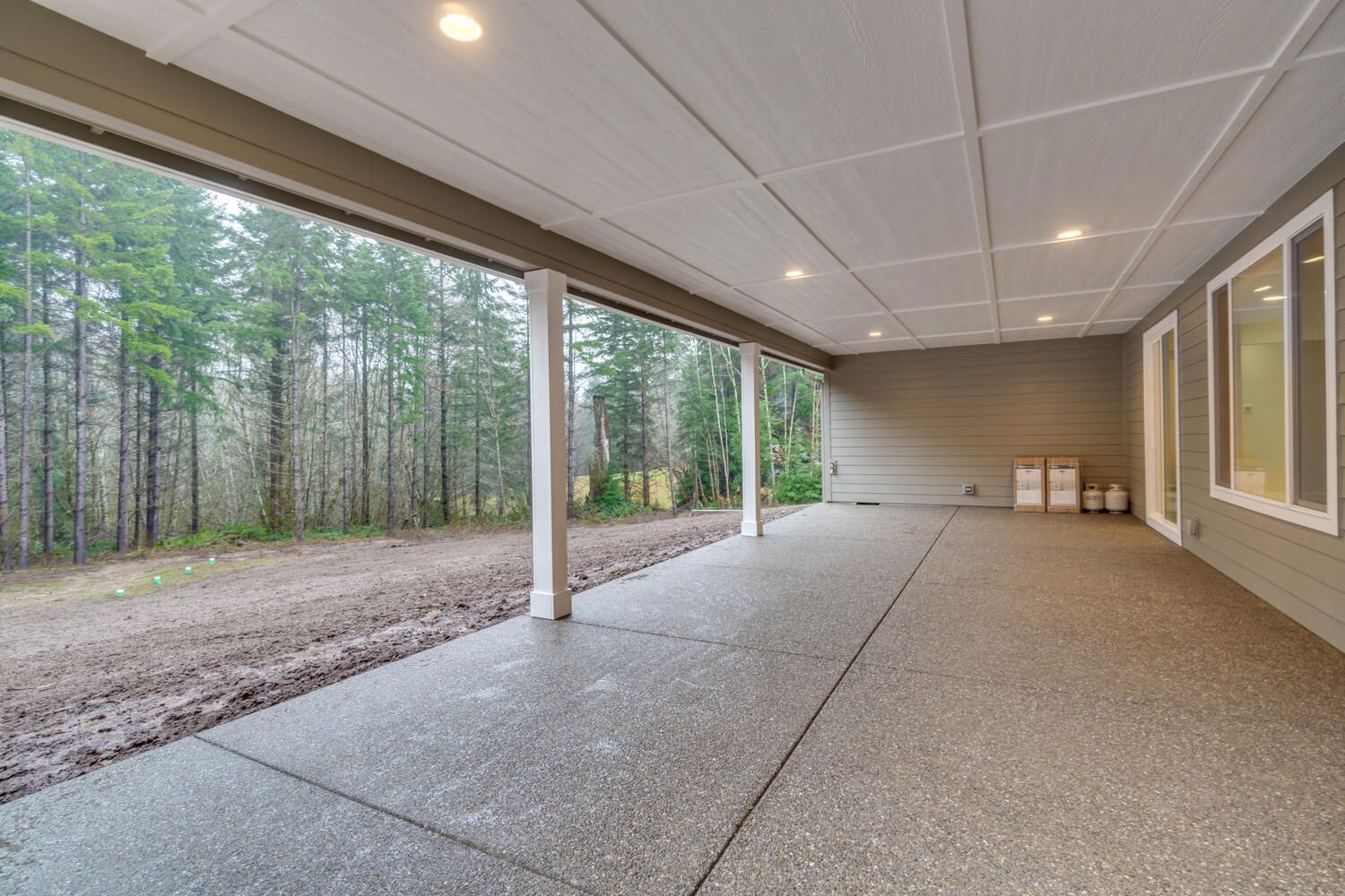 A large covered patio with a view of a forest.