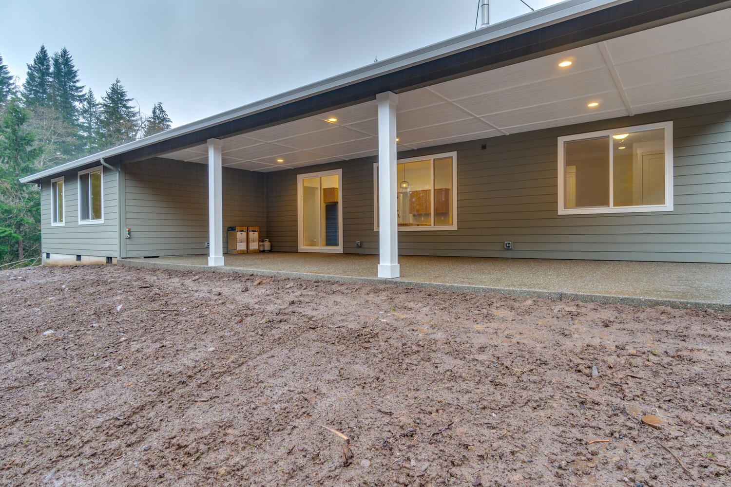 The back of a house with a covered patio and a lot of dirt in front of it.