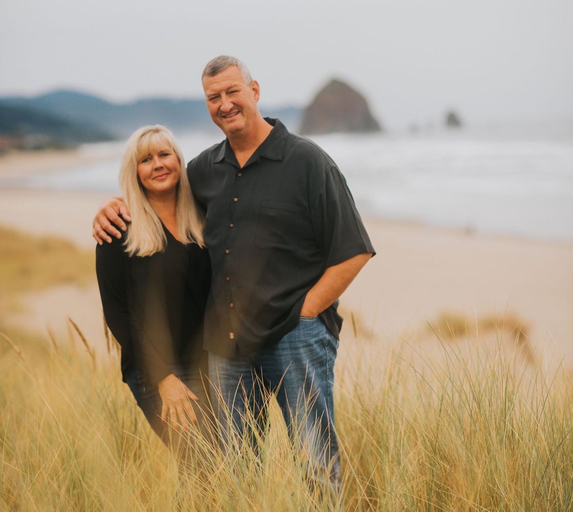 A man and a woman are posing for a picture in a field