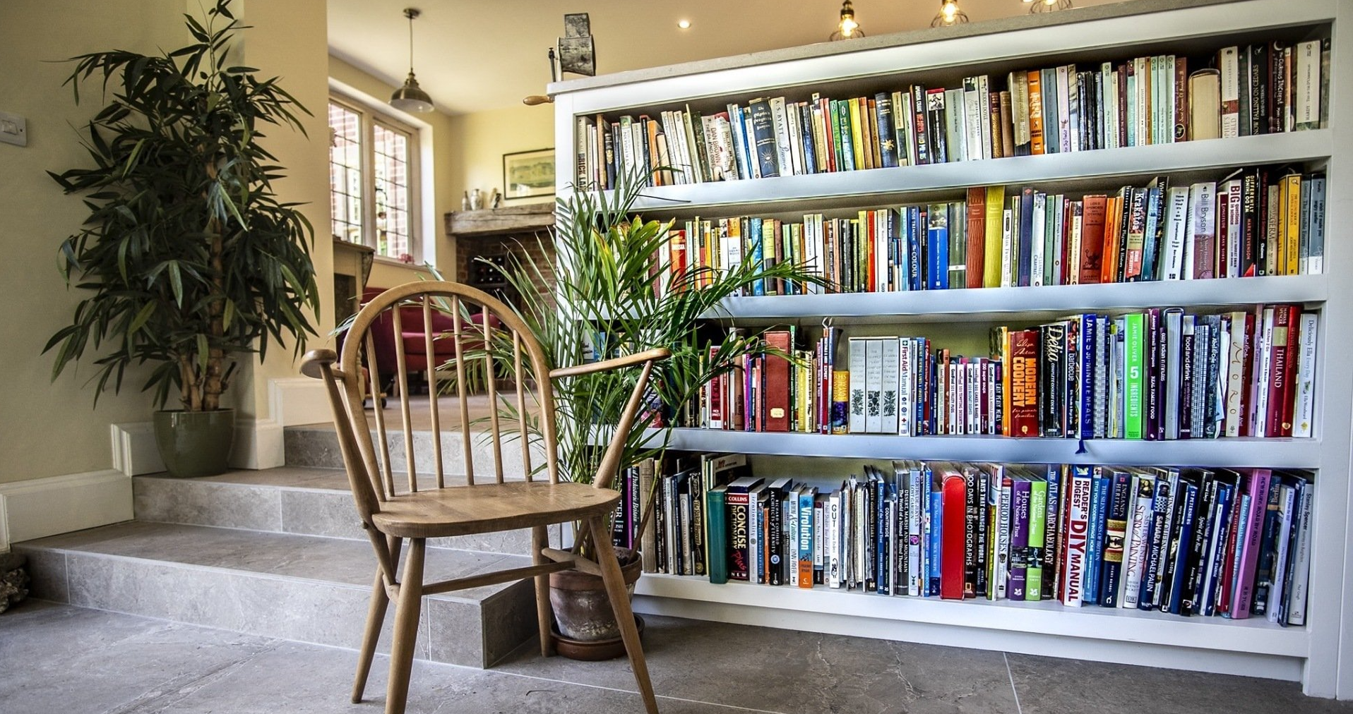 wooden chair and bookcase full of books