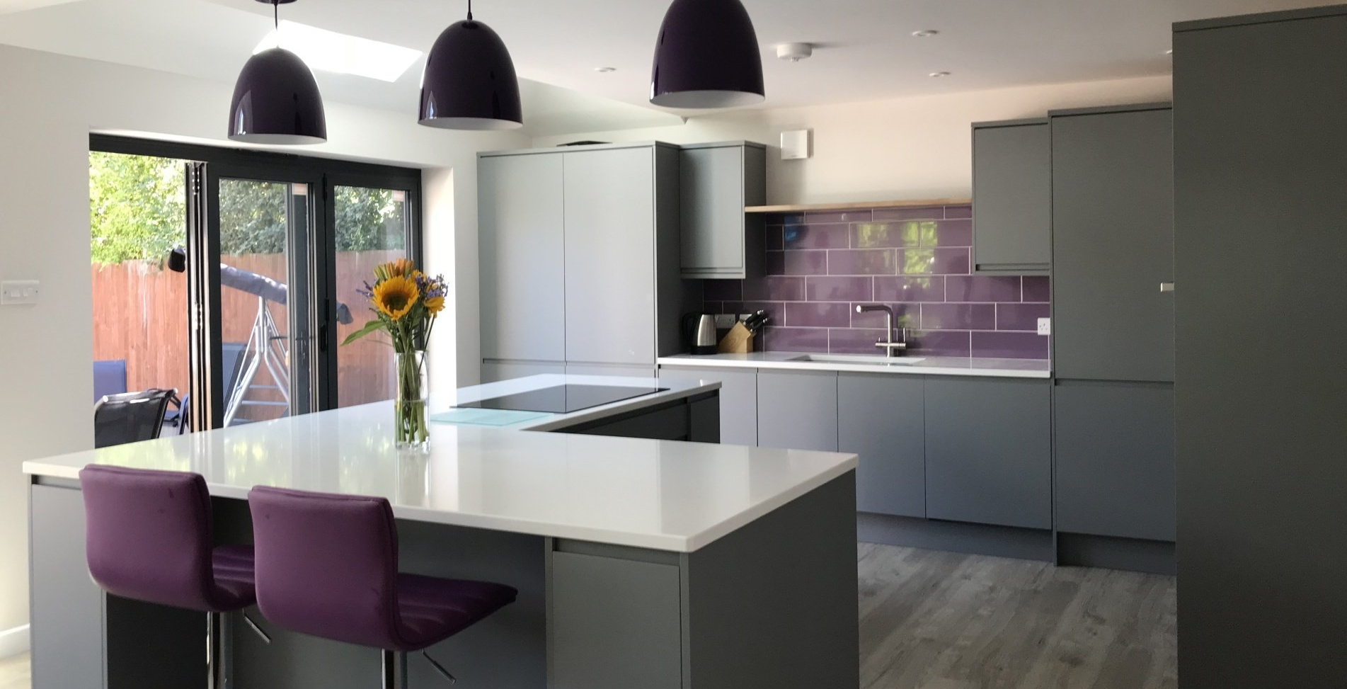 modern kitchen with purple chairs, splashback and lamps