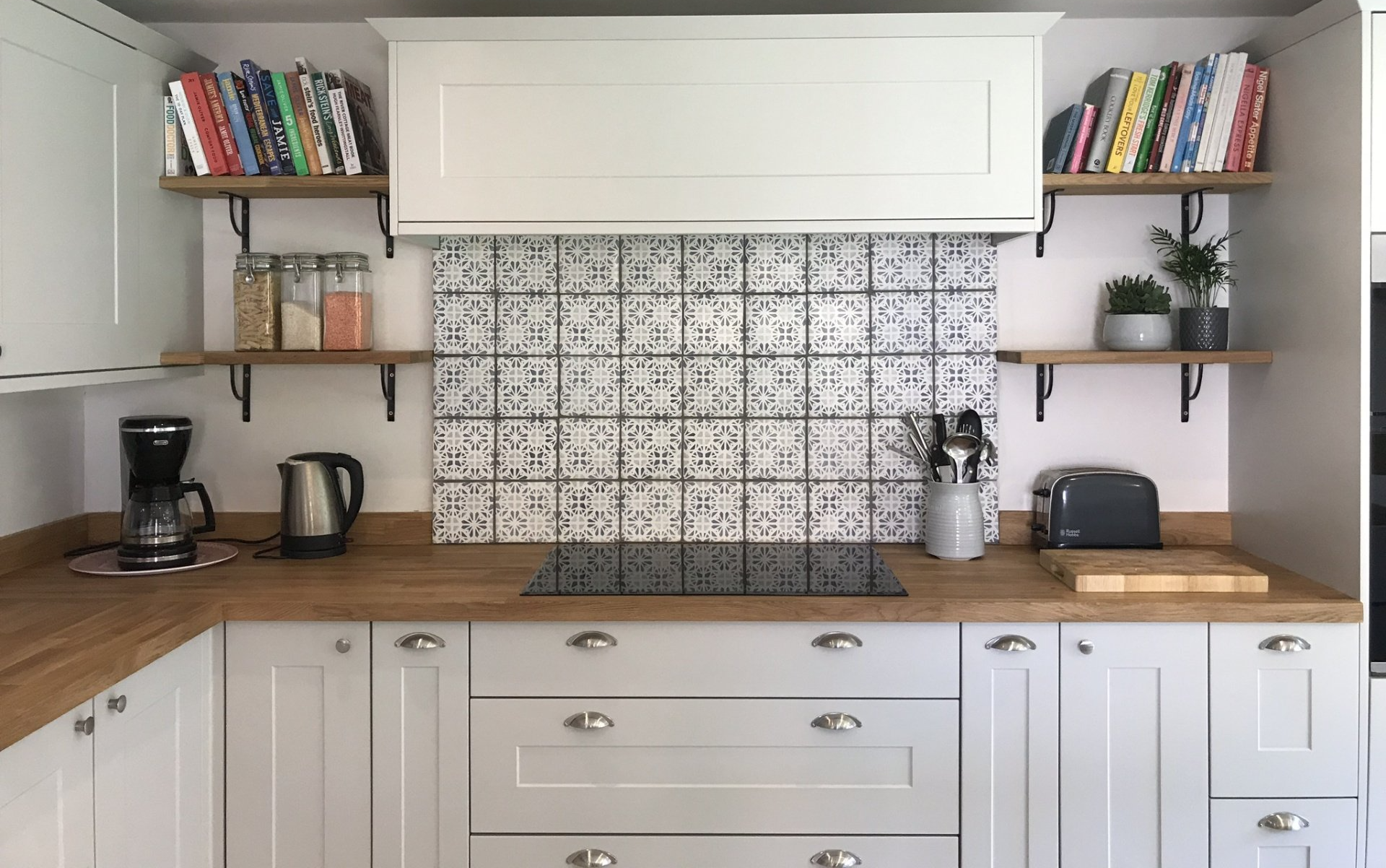 White shaker kitchen with wooden worktops, open shelves and patterned tile splashback