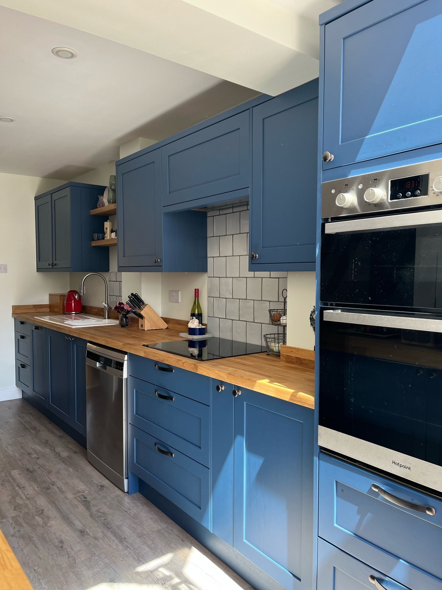 Traditional galley kitchen with blue doors, oak worktops and eye level ovens