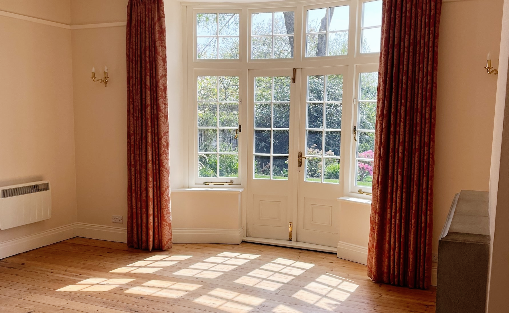 empty living area with long red curtains framing french doors
