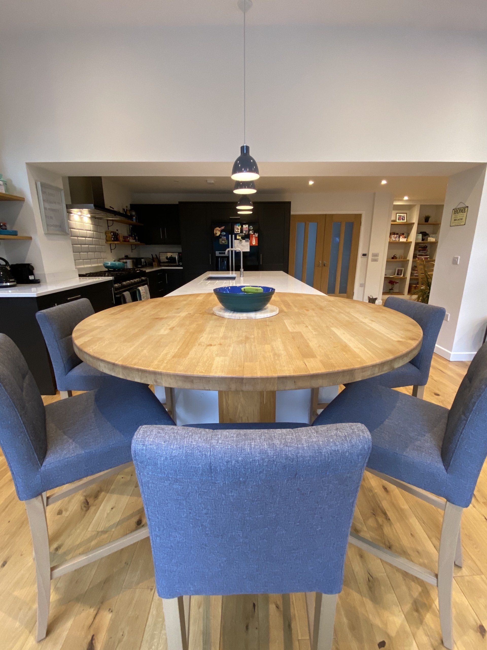 round wooden dining table with blue upholstered chairs