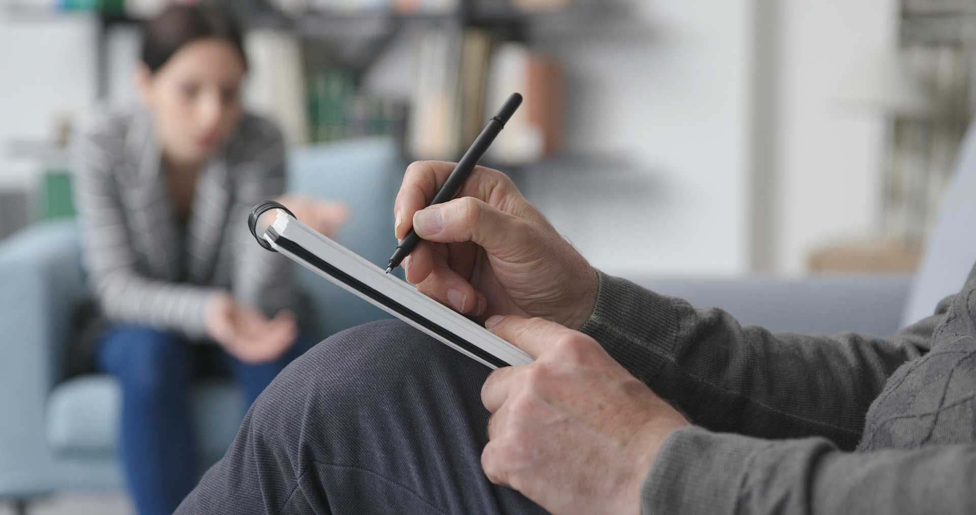 Professional therapist listening to the patient and writing notes 
