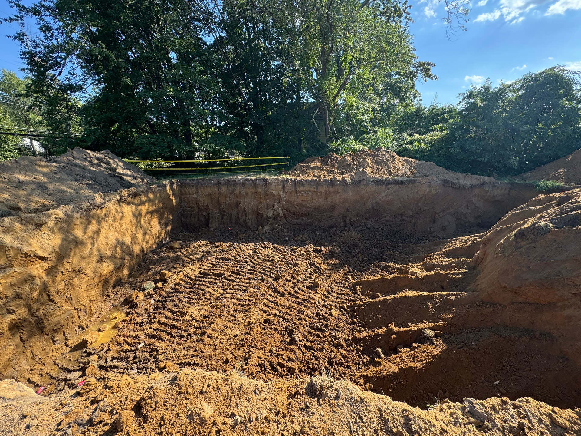 Excavated site prepared for utility installation or foundation work during an early construction phase.