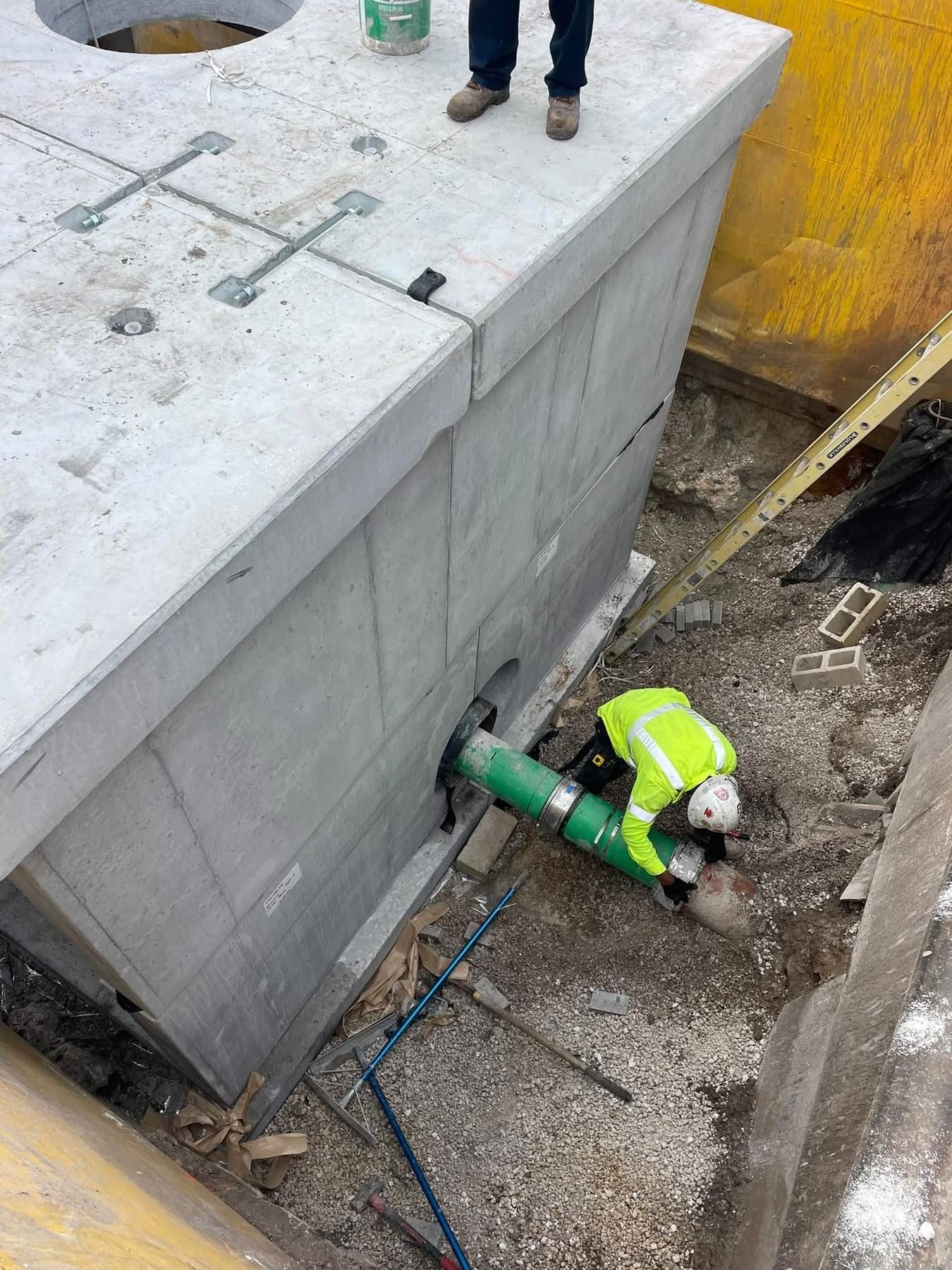 Workers installing a large precast concrete vault for underground utility infrastructure.