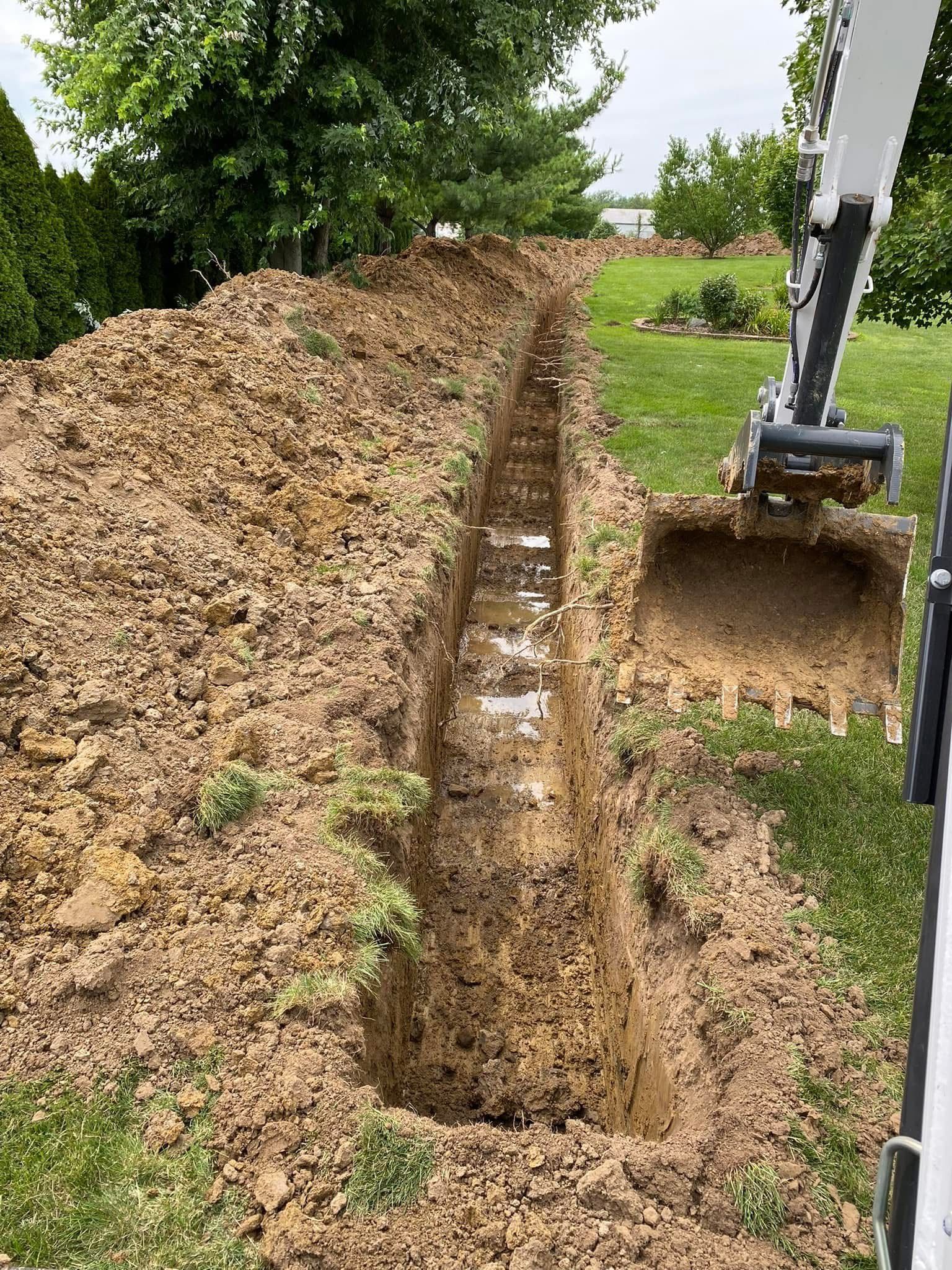Excavator digging a narrow trench for underground utility installation in a residential yard.