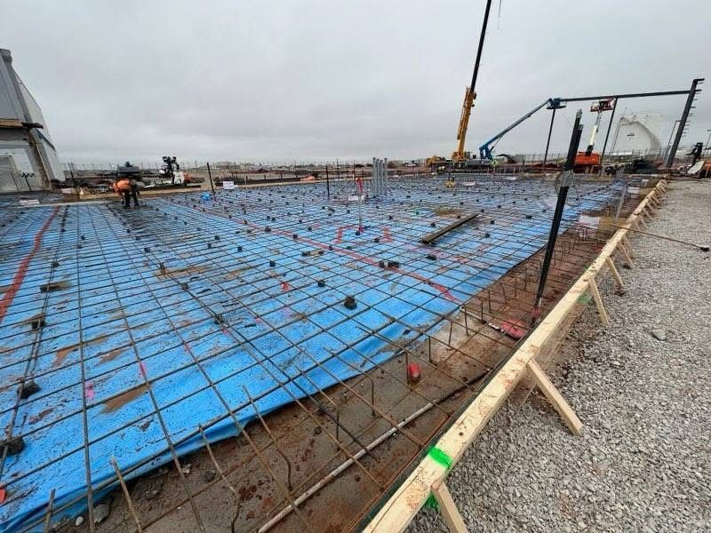Construction team installing reinforced concrete slab with rebar framework for a large commercial project.